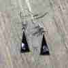 Black triangle earrings with shell, on wood